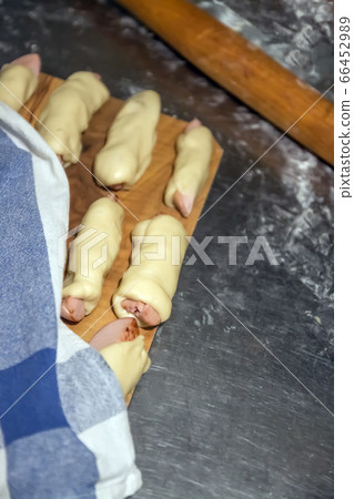 Prepared raw sausages in the test before baking lie on a table under a napkin. Concept, home cooking 66452989