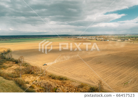 Aerial View. Tractor Plowing Field In Spring Season. Beginning Of Agricultural Spring Season. Cultivator Pulled By A Tractor In Countryside Rural Field Landscape 66457523