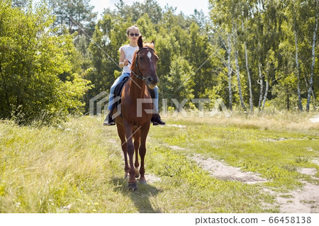 Teenager girl riding a brown horse, horseback riding for people in the park 66458138