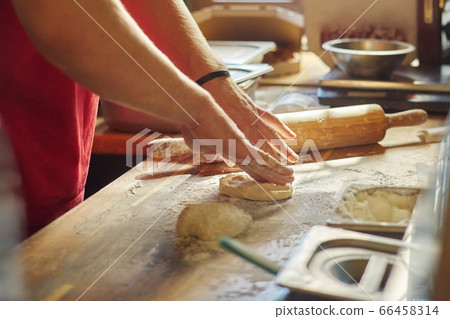 Hands of male baker with flour dough preparing food on wooden table 66458314