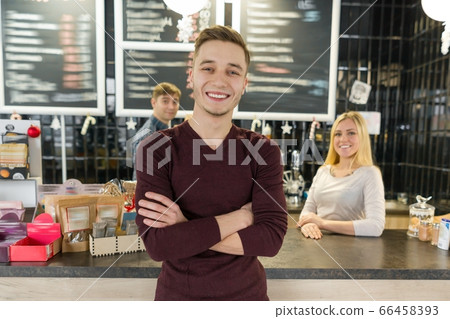 Young team of three cafe workers, people posing and smiling at coffee bar near bar counter Young team of three cafe workers, people posing and smiling at coffee bar near bar counter 66458393