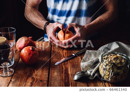 Man Opens Pomegranate. 66461340