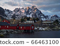 Classic red rorbu next to mountain ranges in Ballstad, Lofoten island, Norway 66463100