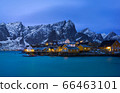 Classic illuminated yellow waterfront rorbu in Reine, Lofoten island, Norway 66463101
