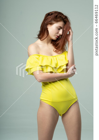 young beautiful girl pose in a yellow bodysuit in the studio 66469112