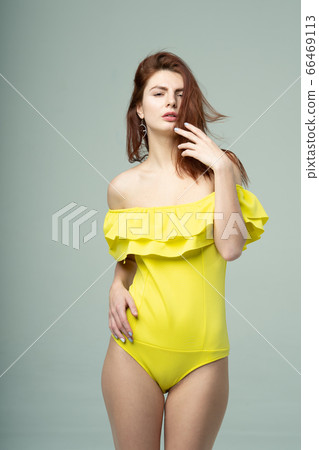 young beautiful girl pose in a yellow bodysuit in the studio young beautiful girl pose in a yellow bodysuit in the studio 66469113