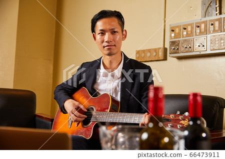 A young man playing the guitar 66473911
