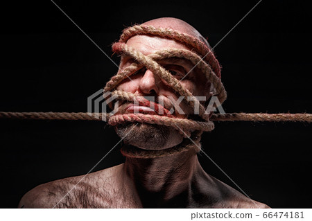 Image of binded bald man with rope on face 66474181