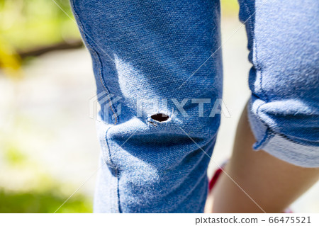 Open hole and copy space in the trousers knee of a walking person 66475521
