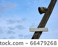 Speaker on a wooden pole with a sign against a blue sky 66479268