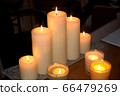 Burning candles on a wooden table against a dark room background 66479269