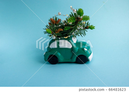 Toy green car with a Christmas tree decorated with a garland, isolated on a blue background with a copy of the space Toy green car with a Christmas tree decorated with a garland, isolated on a blue background with a copy of the space 66481623