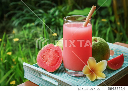 Guava smoothie in glass with bamboo drinking straw 66482314