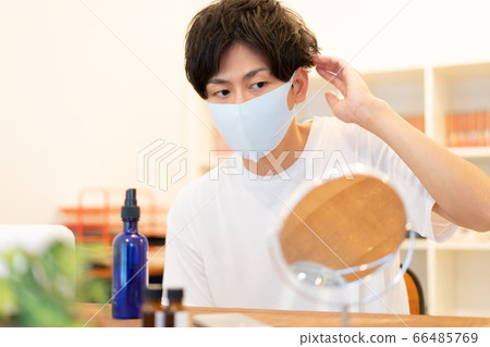 一個二十多歲的男人準備帶著淡藍色面具穿著時尚出去 一個二十多歲的男人準備帶著淡藍色面具穿著時尚出去 66485769
