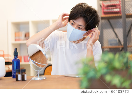 一個二十多歲的男人準備帶著淡藍色面具穿著時尚出去 66485773