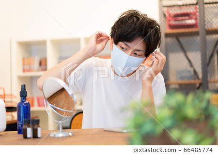 A man in his twenties preparing for going out with a light blue mask wearing fashion 66485774