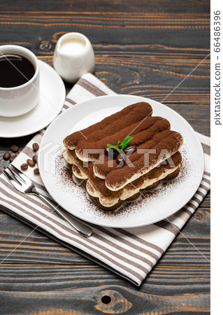 Classic tiramisu dessert on ceramic plate, milk or cream and cup of coffee on wooden background 66486396