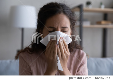 Close up sick woman blowing nose, holding paper tissue 66487063
