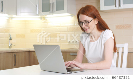 Young beautiful woman smiling and working with computer at home in kitchen Young beautiful woman smiling and working with computer at home in kitchen 66487331