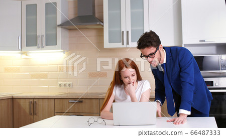 Business couple smiling working with laptop at home in kitchen Business couple smiling working with laptop at home in kitchen 66487333