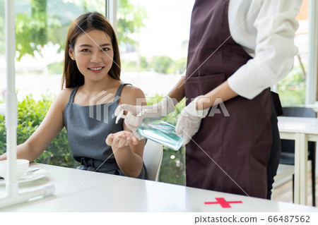 Waitress push hand sanitizer for customer. Waitress push hand sanitizer for customer. 66487562