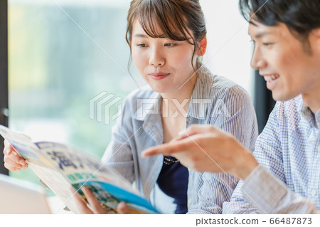 Men and women making plans while looking at travel brochures 66487873