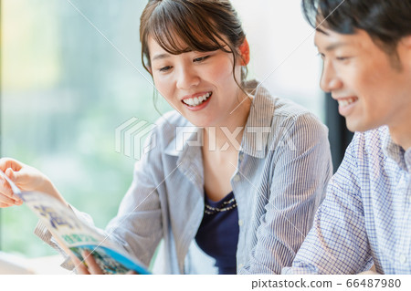 Men and women making plans while looking at travel brochures 66487980