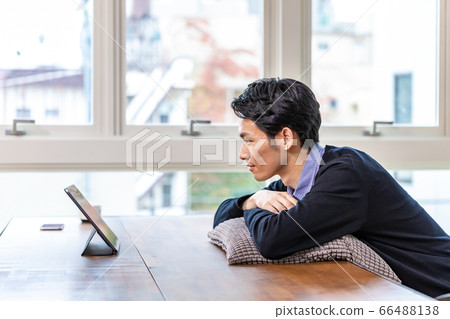 Man relaxing and looking at tablet at home 66488138