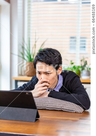 Man relaxing and looking at tablet at home 66488169