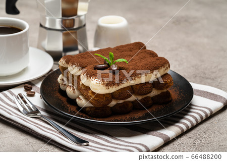 Classic tiramisu dessert on ceramic plate, milk or cream and cup of coffee on concrete background Classic tiramisu dessert on ceramic plate, milk or cream and cup of coffee on concrete background 66488200