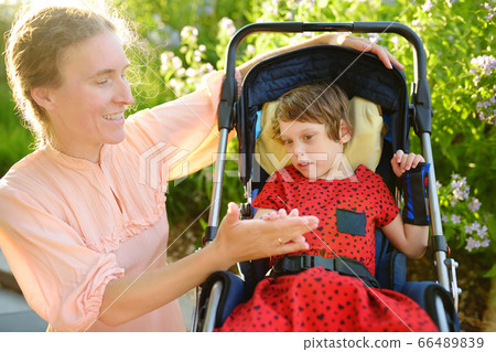 Woman with disabled girl in a wheelchair walking 66489839