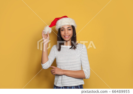 Happy girl in Santa hat on yellow background Happy girl in Santa hat on yellow background 66489955