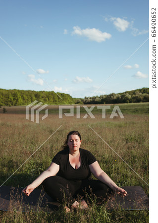 Overweight woman doing yoga meditation outdoors Overweight woman doing yoga meditation outdoors 66490652