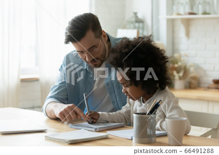 Male tutor helps understand arithmetic task to little African girl 66491288