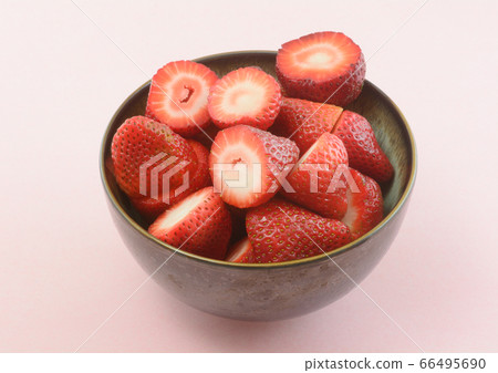 Ceramic bowl of freshly cut raw strawberries on pink background Ceramic bowl of freshly cut raw strawberries on pink background 66495690