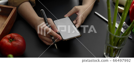 Female student using mock-up smartphone in cooking 66497992