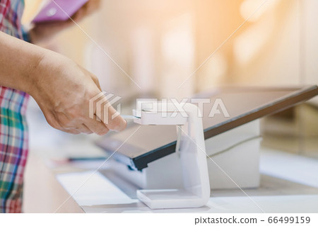 Close up to young man use the identification card inserted into the identity verification machine to receive ticket to the museum. Selective focus. 66499159