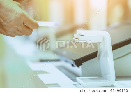 Close up to young man use the identification card inserted into the identity verification machine to receive ticket to the museum. Selective focus. 66499160