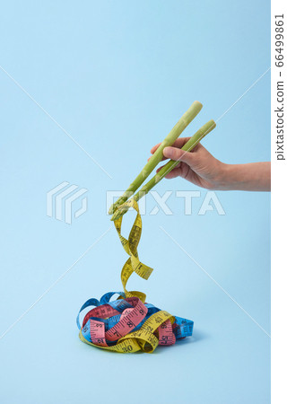 Woman's hand is taking measure tapes by asparagus spears as sticks. 66499861