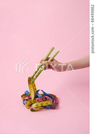Woman's hand with asparagus sticks is taking measuring tapes. 66499862