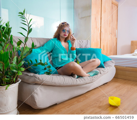 Woman sitting on a sofa smoking sigarette. Self 66501459