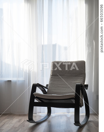 Rocking chair in the morning sunshine. Light streams through the rocker forming patterns on the floor. 66503096