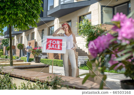 Smiling young woman standing with a table for sale Smiling young woman standing with a table for sale 66503168