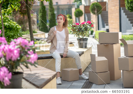 Young pretty woman in white pants sitting on the cardboards Young pretty woman in white pants sitting on the cardboards 66503191