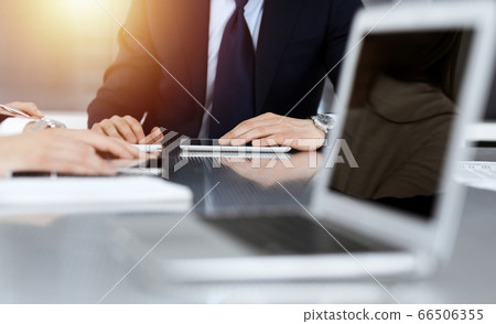 Business people discussing contract while working together in sunny modern office. Unknown businessman and woman with colleagues or lawyers at meeting 66506355