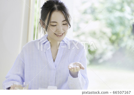 A young woman trying to take medicine in the living room A young woman trying to take medicine in the living room 66507167