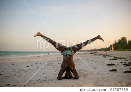 Young Attractive Muscular and Strong Athletic Black African Man at the White Sand Beach Training Acrobatics and Jumping Gymnastics Beach Performance 66507289
