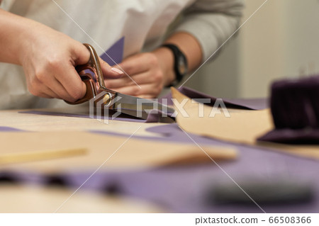 female hand with the scissors cutting fabric. female hand with the scissors cutting fabric. 66508366