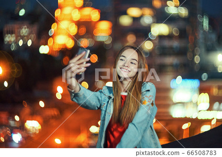Teen girl on cityscape background making self portrait with her smart phone Teen girl on cityscape background making self portrait with her smart phone 66508783