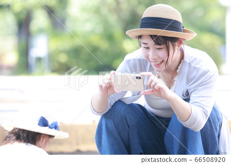 媽媽給孩子拍照在智能手機的沙箱中玩 媽媽給孩子拍照在智能手機的沙箱中玩 66508920
